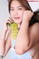 A woman holding a bunch of grapes in her hand.