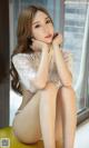 A woman in a white lingerie sitting on a yellow stool.