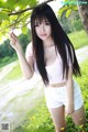 A young woman posing under a tree in a field.