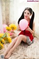 A woman in a red dress holding a pink balloon.