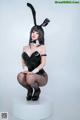 A woman in a bunny costume sitting on a white pedestal.