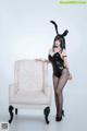 A woman in a bunny costume posing next to a chair.