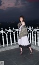 A woman standing on a balcony at night.