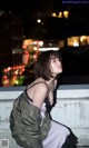 A woman sitting on a ledge in a city at night.