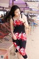 A woman in a black and red dress standing on a beach.