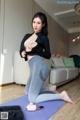 A woman sitting on a yoga mat in a living room.