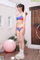 A woman in a bikini standing next to a pink ball.
