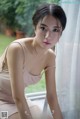 A woman in a pink dress sitting on a window sill.