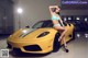 A woman in a bikini sitting on a yellow sports car.