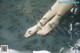 A woman's feet in the water surrounded by fish.