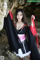 A woman in a black and red kimono posing for a picture.