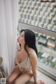 A woman sitting on a window sill looking out a window.