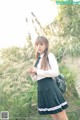 A woman in a school uniform standing in a field.