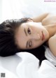 A woman laying on top of a bed covered in white sheets.