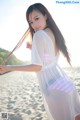 A woman in a white dress standing on a beach.