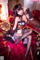 A woman in a black and red lingerie sitting on a red couch.