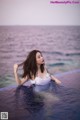 A woman in a white bathing suit sitting in a pool.