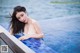 A woman in a white bikini sitting in a pool.