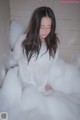 A woman sitting in a bathtub filled with foam.