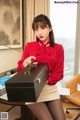 a woman in a red shirt and skirt sitting at a desk