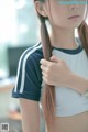 A woman with long brown hair wearing a blue and white shirt.