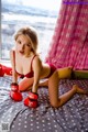 A woman in a red bikini and red boxing gloves on a bed.