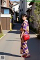 A woman in a purple kimono is walking down the street.