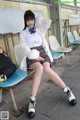 A woman in a school uniform is sitting on a bench.