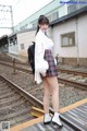 A woman in a school uniform standing on a train platform.