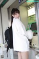 A woman standing in front of an atm machine with a backpack.