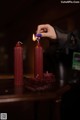 A person lighting a red candle on a table.