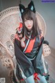 A woman in a black and red kimono sitting on a chair.