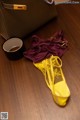 A pair of yellow shoes and a purple bra on a wooden floor.