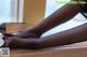 A woman in black stockings is sitting on a window sill.