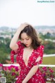 A woman in a red dress posing on a balcony.