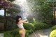 A woman in a bikini holding a hose in a garden.