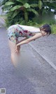 A woman in a floral dress bending over on the ground.