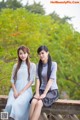 Two young women sitting on a wooden bridge. 