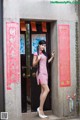 A woman in a red and white checkered dress standing in front of a door.